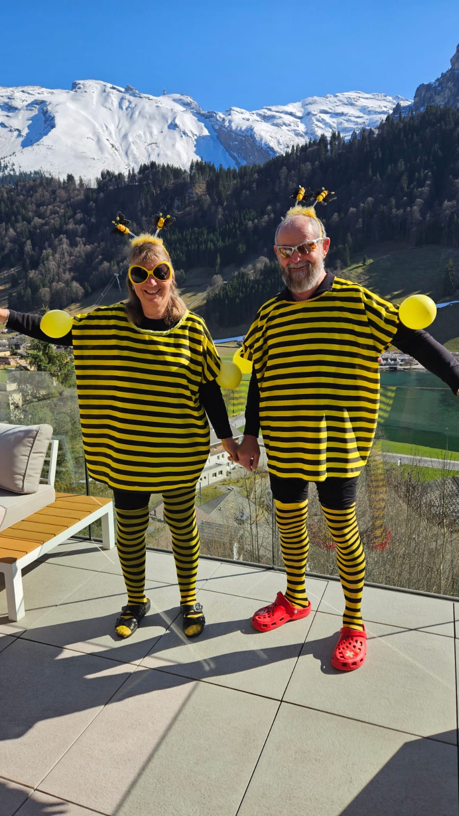 Andrea's parents in playful bee costumes on a terrace in front of the Swiss mountains